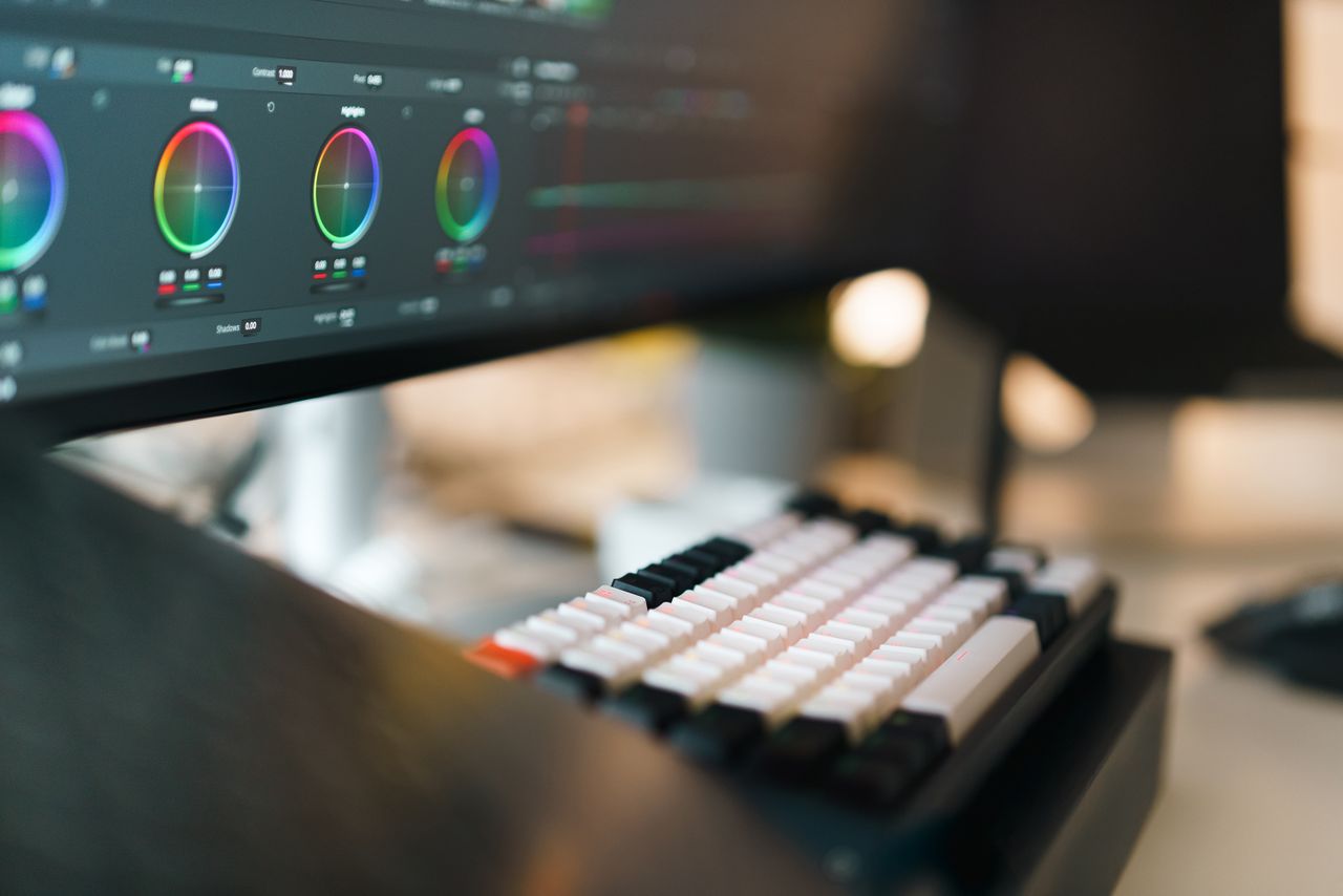 A close-up of a video editing setup featuring a mechanical keyboard and color grading on a monitor.